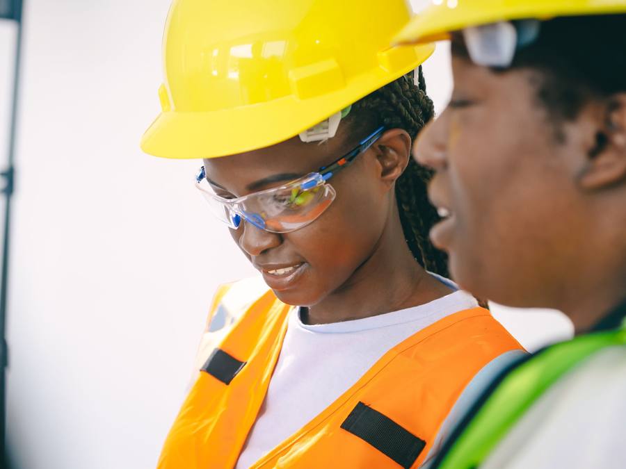 Duas engenheiras africanas com capacete e colete de segurança